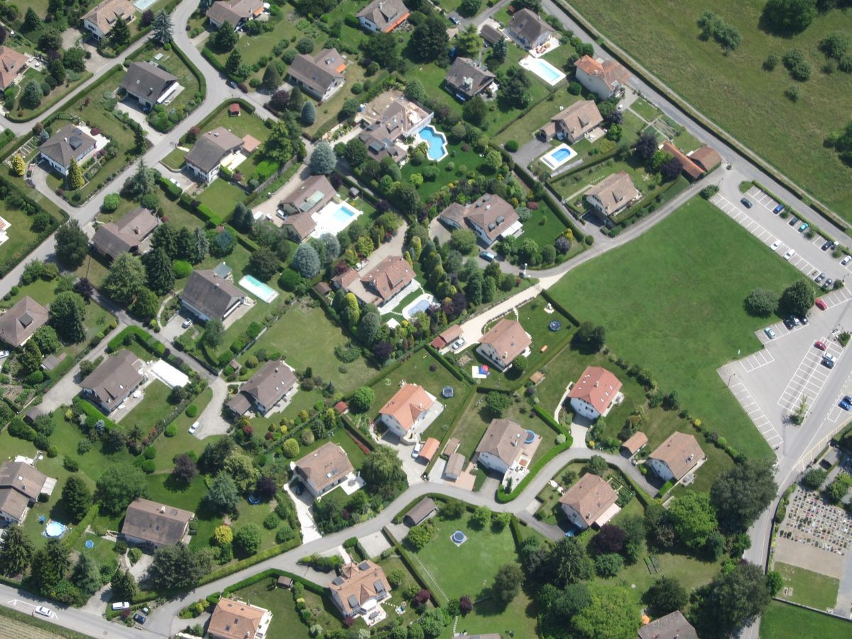 Swiss Upper Class Villa neighborhood with neat lawns and swimming pool seen from above from a paraglider's perspective near Montreux