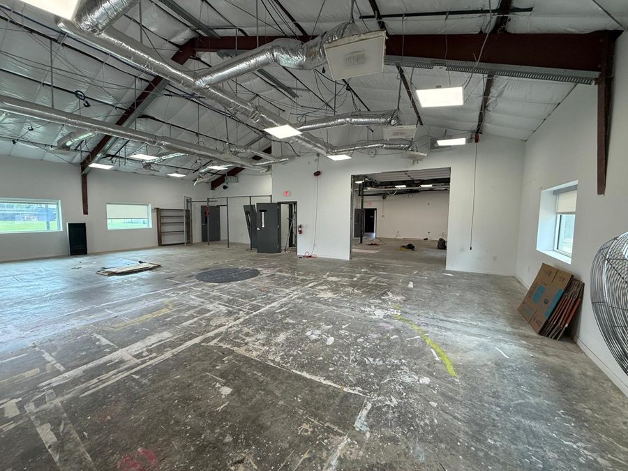 The room cleared: a bare slab marked with old layout lines, ductwork and light panels still overhead
