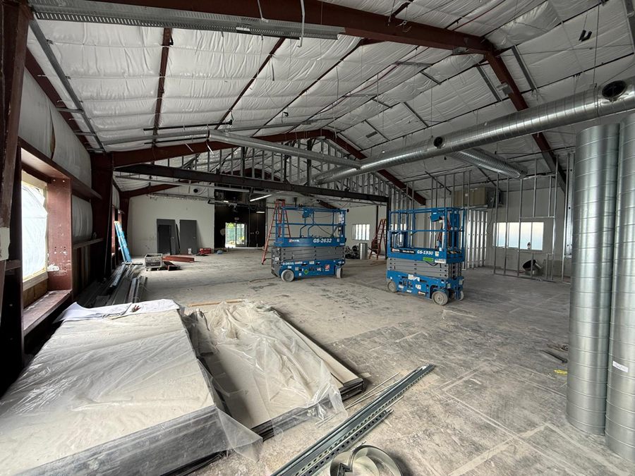 Construction: scissor lifts under the roof, lengths of spiral duct stacked on end and board stacked under plastic